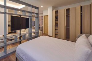 Ein Schlafzimmer mit Bett, Fernseher, Schreibtisch und Kleiderschrank.