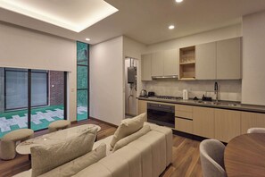 A modern kitchen with built-in appliances, a dining area with a round table and chairs, and a sliding glass door leading to an outdoor area with a patterned floor. - Studio boutique  Free parking & rooftop - Oniria (Ciudad de México)