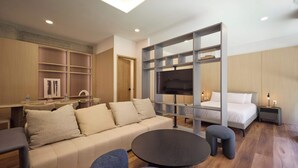Una habitación de hotel moderna con sofá, una mesa redonda, televisor y cama.
