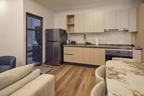 Eine kleine Küche mit Kühlschrank, Herd und Spüle. Es gibt einen Essbereich mit Tisch und Stühlen.