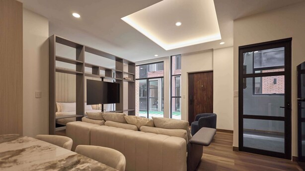Una sala de estar moderna con un sofá, un televisor y una zona de comedor con una mesa de mármol.