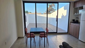 A spacious living area with a sliding glass door leading to a balcony, a dining table with chairs, a sofa, and a kitchenette. - Modern 1-Bed Apartment in Miguel Hidalgo with Balcony (Ciudad de México)