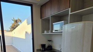 A modern kitchen with wooden cabinets, a built-in microwave, a refrigerator, and a sliding glass door leading to an outdoor area. - Modern 1-Bed Apartment in Miguel Hidalgo with Balcony (Ciudad de México)