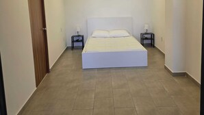 A bedroom with a bed, two bedside tables, and a wooden door. - Modern 1-Bed Apartment in Miguel Hidalgo with Balcony (Ciudad de México)