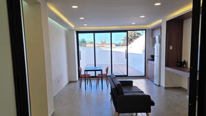 A spacious living area with a dining table and chairs, a sofa, and a kitchen area with a refrigerator. - Modern 1-Bed Apartment in Miguel Hidalgo with Balcony (Ciudad de México)