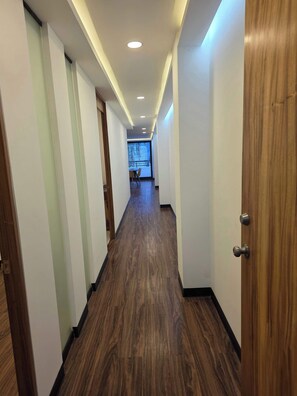 A hallway with wooden flooring, white walls, and a door on the right.