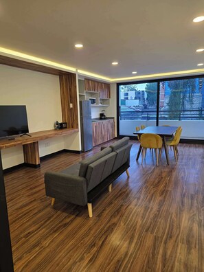 Una sala de estar moderna con sofá, mesa de comedor y área de cocina.