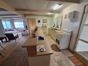 A hotel room with a kitchenette, a dining area with a table and chairs, and a bed with a view.