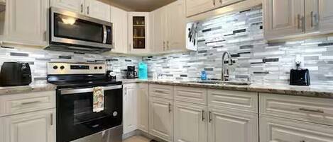 A modern kitchen with white cabinetry, stainless steel appliances, and a tiled backsplash.