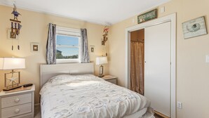 Un dormitorio con cama, lámparas de noche, una ventana con cortinas, una puerta y adornos en la pared.