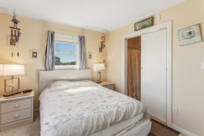 A bedroom with a bed, bedside lamps, a window with curtains, a door, and wall decorations. - Only a 2 minute walk to the Avon beach! Private Pool, Hot Tub, Luggage Lift (Avon)