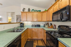 A kitchen with wooden cabinets, a microwave, a stove, and a dishwasher. - Only a 2 minute walk to the Avon beach! Private Pool, Hot Tub, Luggage Lift (Avon)