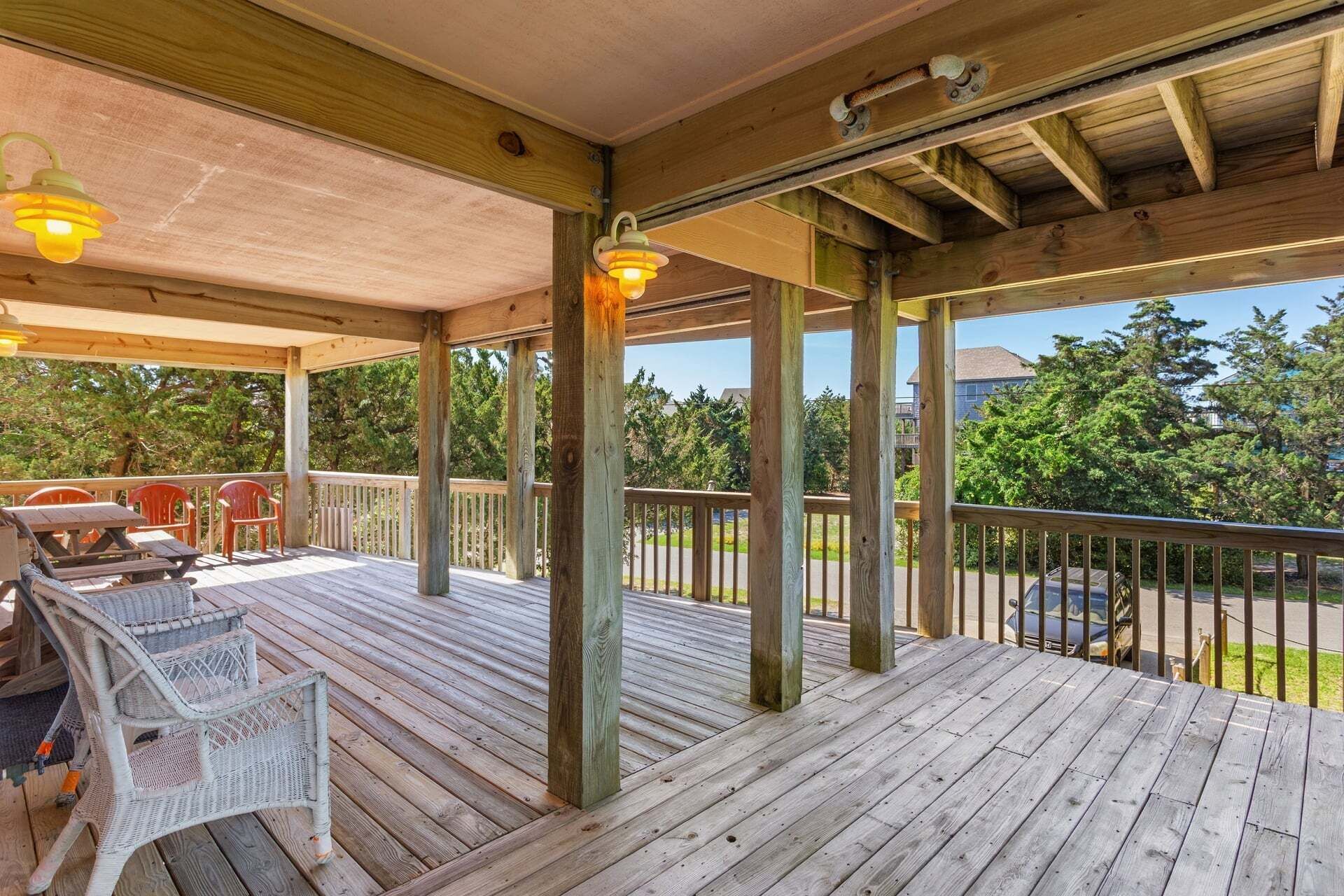 Une terrasse en bois, dotée de meubles d’extérieur et d’une rambarde, qui offre une vue sur un quartier résidentiel.