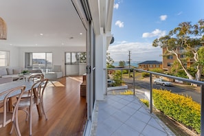 Un appartement moderne doté d’un balcon donnant sur une rue et sur un espace verdoyant.