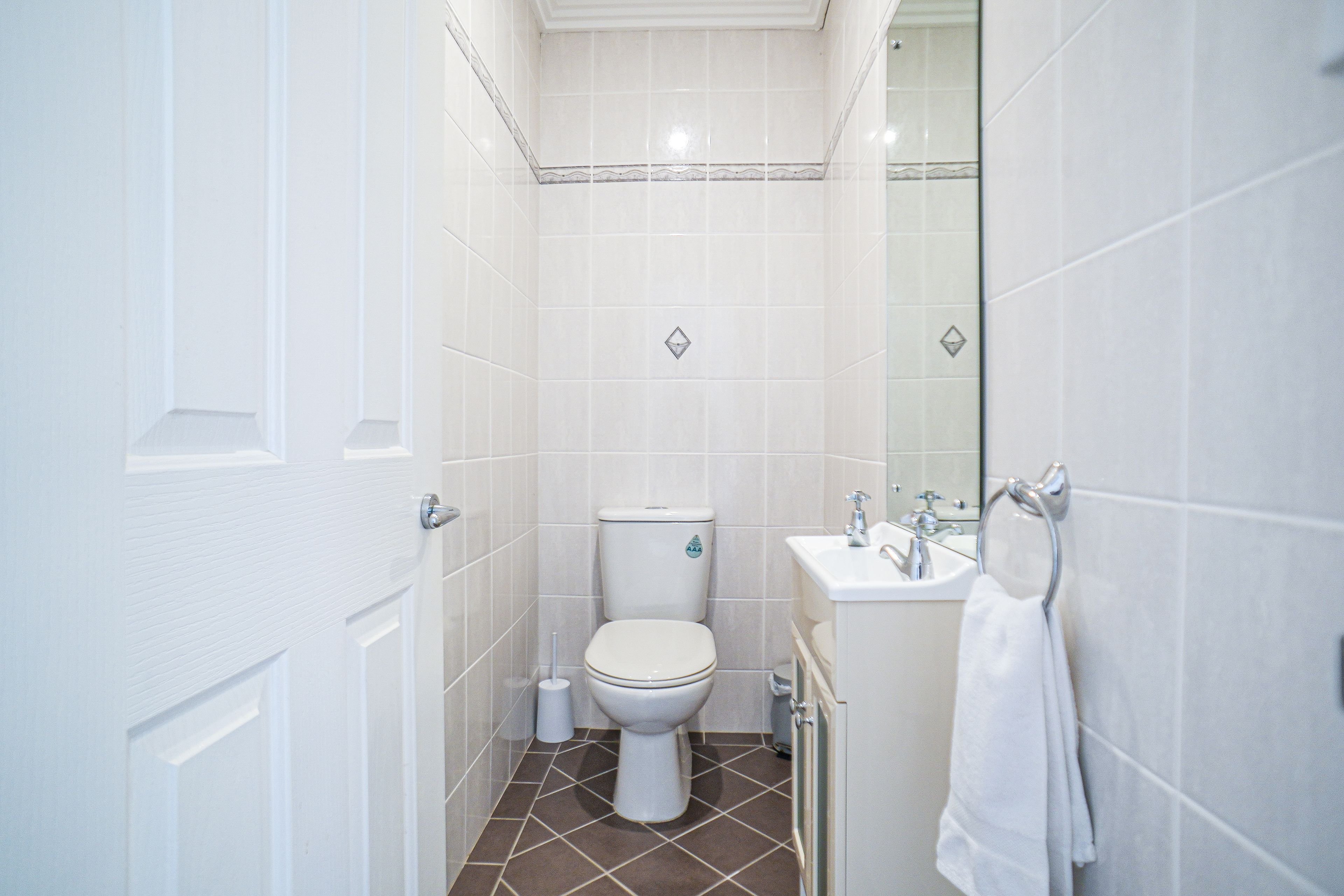 A bathroom with a toilet, sink, and mirror.