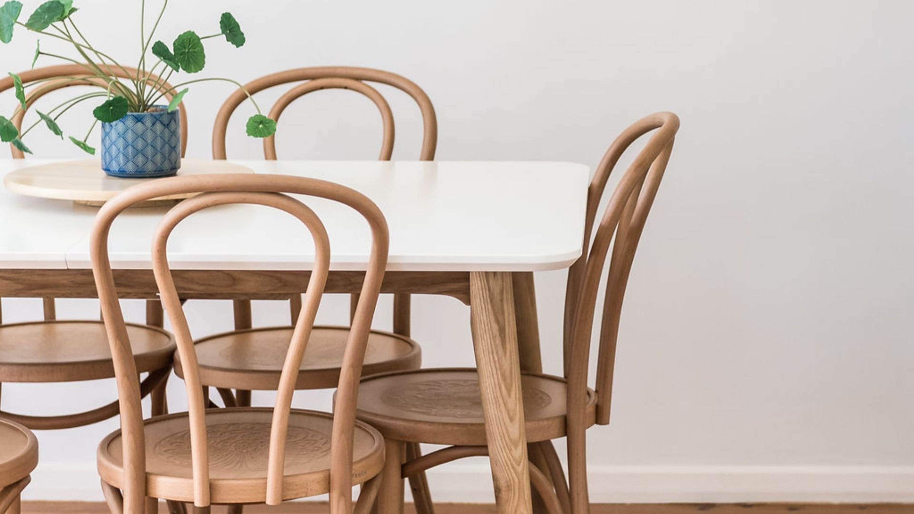 Une table à manger avec quatre chaises en bois et une plante en pot.