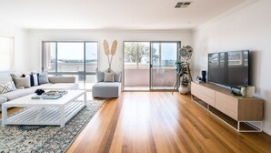 A modern living room with a sofa, coffee table, and TV. - Summer House - A stylish coastal retreat in Shoal Bay (Shoal Bay)