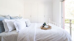 Ein Schlafzimmer mit einem Bett, Kissen, einem Korb und einem Fenster mit Blick.