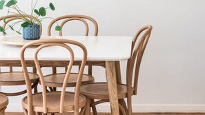 Ein Esstisch mit sechs Holzstühlen, einem Blumentopf und einer weißen Tischdecke.