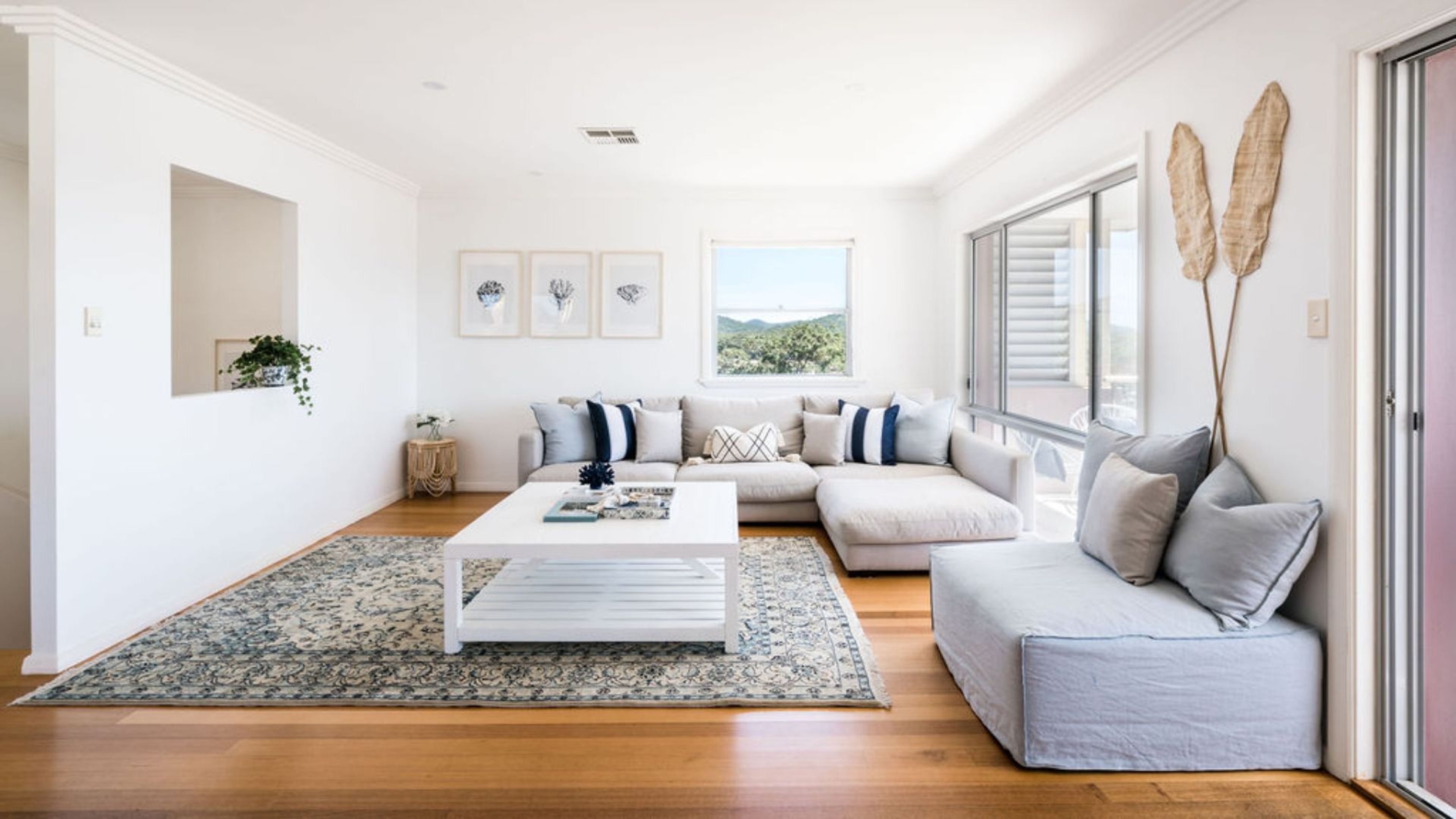 A modern living room with a sectional sofa, a coffee table, and a large window with a view.