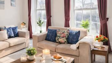 A living room with two sofas, a coffee table, and a window with curtains.