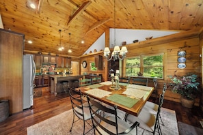 A spacious kitchen with wooden cabinets, a large island, and a dining area with a wooden table and chairs. - Spacious Cabin Retreat with Hot Tub & Game Room (Sugar Grove)