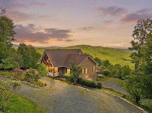 Ein Haus mit geneigtem Dach, einer Veranda und Blick auf einen bewaldeten Hang.
