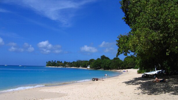 Ein Strand mit einem Boot, blauem Himmel und ruhiger See.
