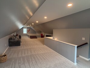 Ein geräumiges Dachzimmer mit hohen Decken, einer eingebauten Sitzbank und einer kleinen Sitzecke.