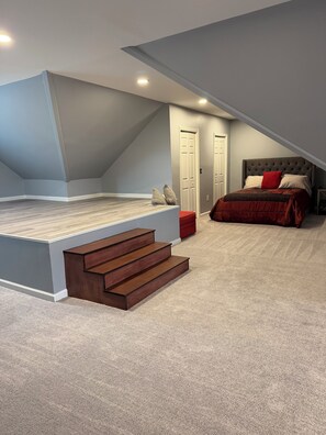 Ein Schlafzimmer mit Schlafkoje, Treppe, einem roten Sessel und einer Tür.