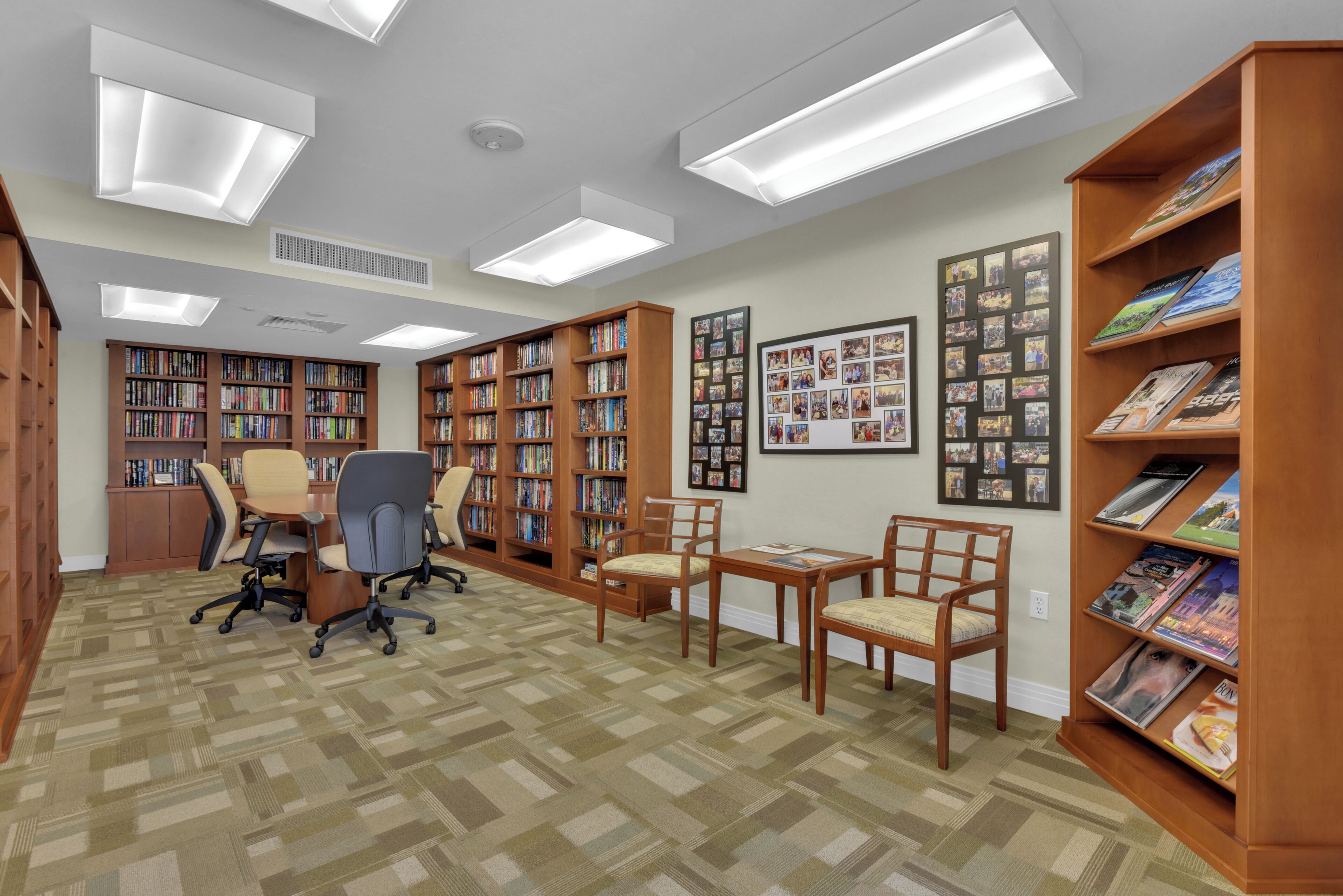 Une bibliothèque avec de nombreuses étagères, quelques chaises et un bureau.