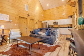 Ein gemütliches Blockhaus-Interieur mit Holzausstattung, einer Couch, einem Esstisch und einer Küchenzeile.