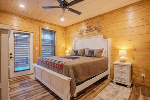A bedroom with a wooden ceiling, a bed with a headboard, a nightstand, and a ceiling fan. - Smoky Escape - Private Hot Tub - Near The Island (Pigeon Forge)