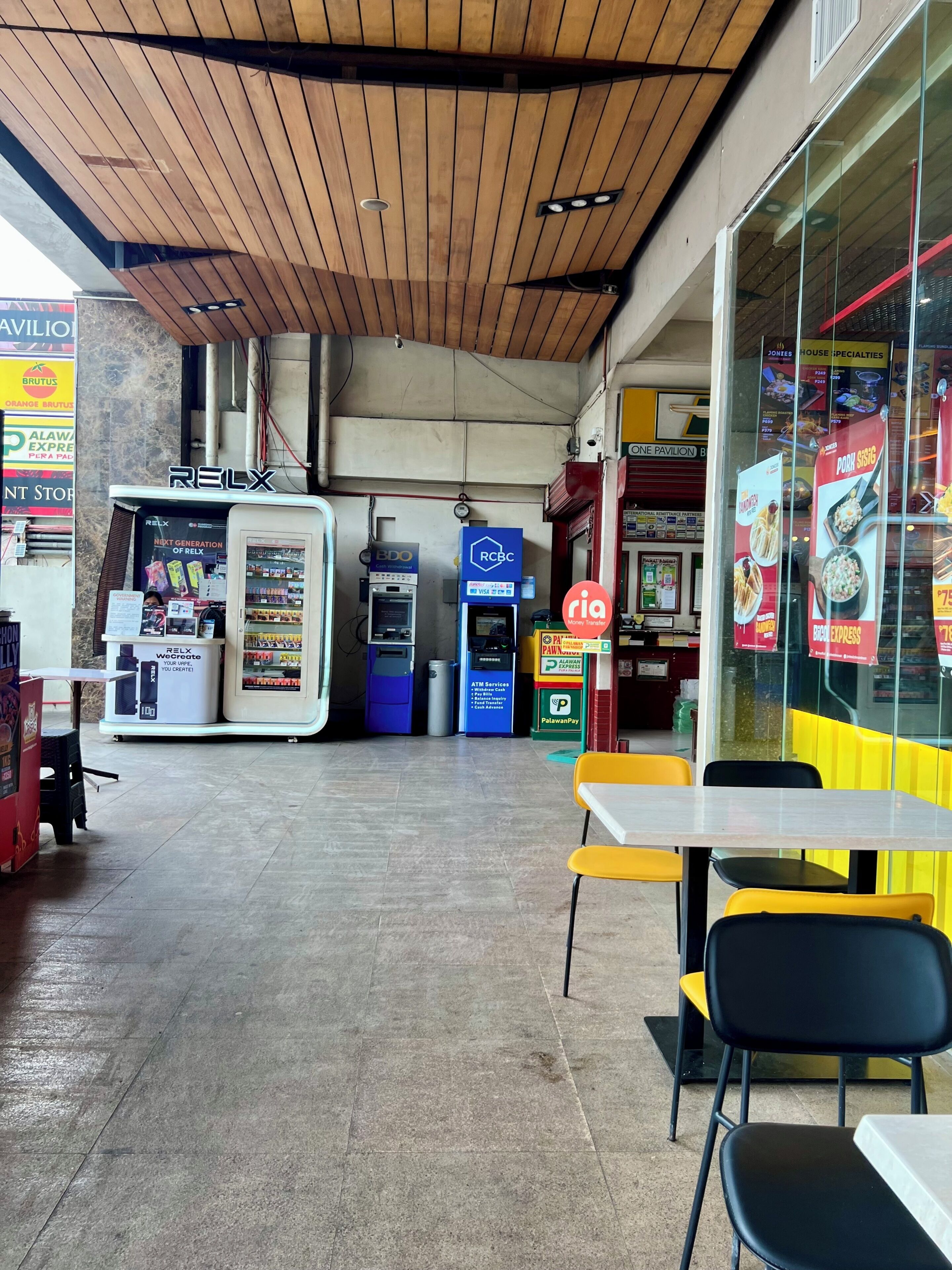 Ein Food-Court mit einem RELX-Kiosk, Geldautomaten und einer Palawand Pay-Station.