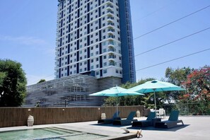 A modern hotel with a pool area, lounge chairs, and umbrellas. - Cebu Sweet Staycation (Cebu City)