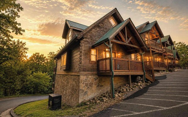 A log cabin-style hotel with a stone foundation, multiple decks, and a stone wall.