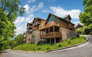A multi-story lodge with a stone facade, wooden balconies, and a curved driveway.
