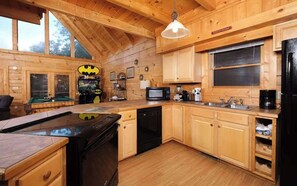 A wooden cabin interior with a kitchen, dining area, and pool table.