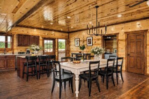 A wooden interior with a dining area, kitchen, and large windows. - Cloud's Rest | Luxury Estate • Pool & Pavilion (Sevierville)