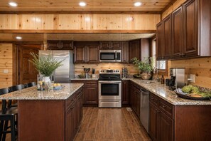 A kitchen with wooden cabinets, stainless steel appliances, granite countertops, and a central island. - Cloud's Rest | Luxury Estate • Pool & Pavilion (Sevierville)