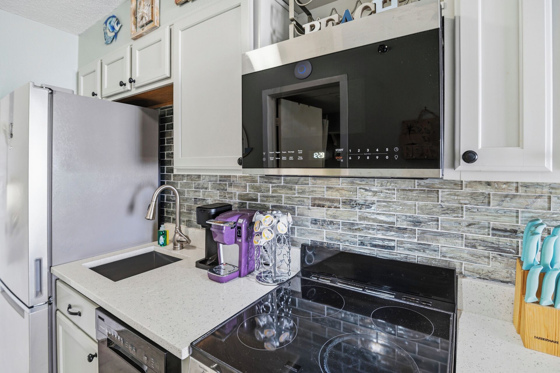 A kitchen with a refrigerator, microwave, stove, and a dishwasher.