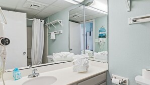 Een badkamer met een wastafel, spiegel, handdoekrek en een haardroger.