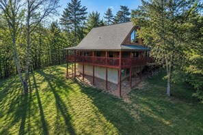 A cabin with a covered porch, surrounded by trees. - Charlie's Creek Retreat | Hot Tub • Game Loft! (Sevierville)