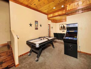 A room with a foosball table, an arcade machine, and a staircase. - Savannah Splash | Hot Tub • Indoor Pool • Pets OK! (Sevierville)