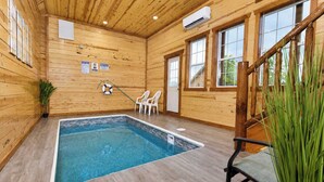 A wooden interior with a pool, chairs, and a lifebuoy. - Savannah Splash | Hot Tub • Indoor Pool • Pets OK! (Sevierville)