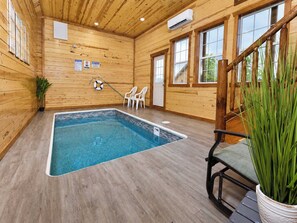 A wooden interior with a pool, chairs, and a lifebuoy. - Savannah Splash | Hot Tub • Indoor Pool • Pets OK! (Sevierville)