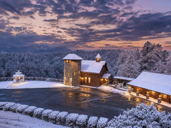 A log cabin with a stone tower, surrounded by snow-covered trees and a frozen lake. - Savannah Splash | Hot Tub • Indoor Pool • Pets OK! (Sevierville)