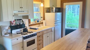 Een keuken met witte kasten, een fornuis, een koelkast en een houten keukeneiland.