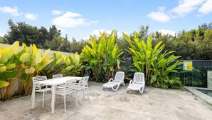Un patio con una mesa y sillas, rodeado de exuberantes plantas tropicales.