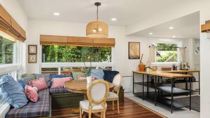 Una sala acogedora con un banco de madera, una mesa de comedor y una lámpara colgante.